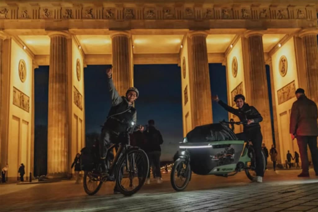 Sione Gruson und Arno Dreef nach ihrer Ankunft mit dem E-Cargobike Lovens Explorer am Brandenburger Tor in Berlin