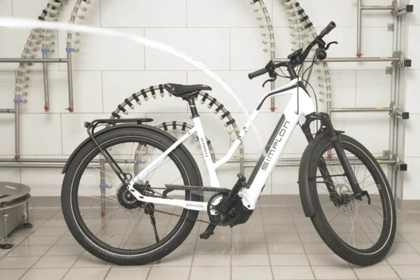 Test auf Spritzwasserschutz an einem E-Bike in einem Prüflabor der Stiftung Warentest